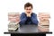 Overwhelmed student with face in hands sitting at his desk between two piles of books