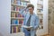 Overwhelmed student in library scratching his head. Stone wall in background