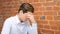 Overwhelmed young businessman with headache thinking at his office