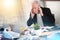 Overworked businessman sitting at a messy desk; multiple exposure