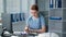 overworked female doctor puts on glasses during hard office work, young woman in front of monitor makes notes on paper