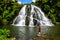 Owharoa Falls with blue sky above and girl tourist person in red t-shirt in the foreground at Coromandel Peninsula