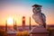 Owl with glasses and a graduation cap sits on the spire of the university, against the backdrop of sunset. Generative AI