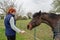 Owner of a horse seen feeding him fresh meadow grass.