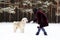 Owner playing with her dog. South Russian Shepherd Dog on a background of winter coniferous forest