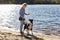 Owner plays with a siberian laika dog on a beach