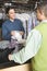 Owner Showing Dry Cleaned Shirts To Customer At Counter