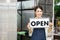 The owner of the tree shop holds a open sign after a long time closed. Cute asian gardener small business open her shop selling