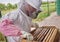 Owning a colony is a huge responsibility. a beekeeper opening a hive frame on a farm.