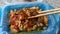 Oyster omelett with hot sauce being picked up with chopsticks in a togo plastic container point of view eating. A favorite in many