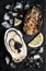 Oysters with black sturgeon caviar and lemon on black slate stone background. Top view, flat lay.