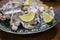 Oysters platter with lemon and ice served on dish