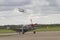 P51 Mustang taxiing on runway with Tiger Moth above in flight.