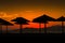 Paceful beach and sea view with silhouettes of sunshades and sunbeds at sunset