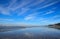 Pacific Northwest ocean beach shoreline. Clouds reflecting on wet sand.