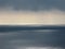 Pacific ocean with clear horizon, ominous clouds, patchy reflections of sunlight