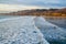 Pacific ocean at high tide and surfers. Golden hills and beautiful cloudy sky on background. Pismo Beach sunset, California