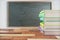 Pack of books on the wooden school desk with blackboard on white