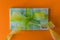 Pack of hundred euro banknotes with green bow-knot on orange desk, gift or dividends concept, european union money