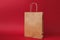 Package bag, brown clear empty blank craft paper bag for takeaway isolated on bright red background. Food products