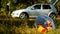 A package of garbage with plastic bottles is lying on the nature, in the background there is a car and people are