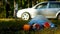 A package of garbage with plastic bottles is lying on the nature, in the background there is a car and people are