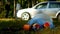 A package of garbage with plastic bottles is lying on the nature, in the background there is a car and people are