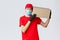 Packages and parcels delivery, covid-19 quarantine delivery, transfer orders. Curious courier in red uniform, gloves and