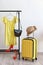 Packed yellow suitcase and rack with clothes