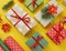 Packing a New Year`s gift. Yellow background. Many gift boxes tied with ribbons. Fir b