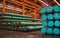 Packs of steel tube stack in layers inside storage area of large distribution warehouse.