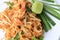 Pad Thai, stir-fried rice noodles with shrimp in white plate with slide lemon and green vegetable. The one of Thailand`s national