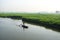 Paddle boat along canal in rapeseed field at morning