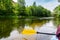 A paddle for rowing yellow in the hands of a girl while kayaking on the river