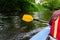 A paddle for rowing yellow in the hands of a girl while kayaking on the river