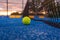 paddle tennis ball near the net on a blue paddle tennis court at sundown, racket sports concept