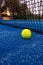 paddle tennis ball near the net on a blue paddle tennis court at sunset