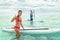 Paddleboard beach people on stand-up paddle boards surfing in ocean on Hawaii beach. Mixed race couple woman and