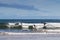 Paddlers in black drysuits doing the stand up paddling at Torquay surf beach, Victoria, Australia