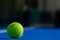 Padel tennis ball on a blue court with the net out of focus in the background