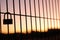 Padlock placed on a fence on a reddish sky sunset background