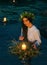 Pagan goddess. water lake, ritual flower wreaths float, candles burning. girl swims in riwer. white vintage shirt