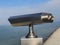 Paid outdoor tourist telescope made of stainless steel on the sea coast over blue sky background