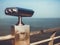 Paid outdoor tourist telescope made of stainless steel on the sea coast over blue sky background