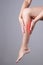 Pain in the calf muscle of the woman. Massage of female feet. Pain in the human body on a gray background