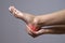 Pain in the foot. Massage of female feet. Pain in the human body on a gray background