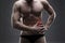 Pain in the left side. Muscular male body. Handsome bodybuilder posing on gray background