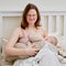 Pain and problems in a woman while breastfeeding a baby. Mother experiences discomfort while breastfeeding