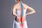 Pain in the spine, woman with backache on gray background, back injury