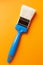 Paint brush on an orange background, vertical orientation, close-up.